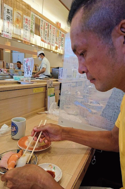 「回転寿しトリトン:清田店」で寿司を食べる男