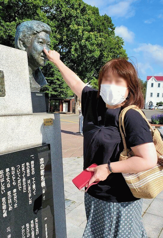 「さっぽろ羊ヶ丘展望台」にある、「恋の街札幌」の記念碑に触る女