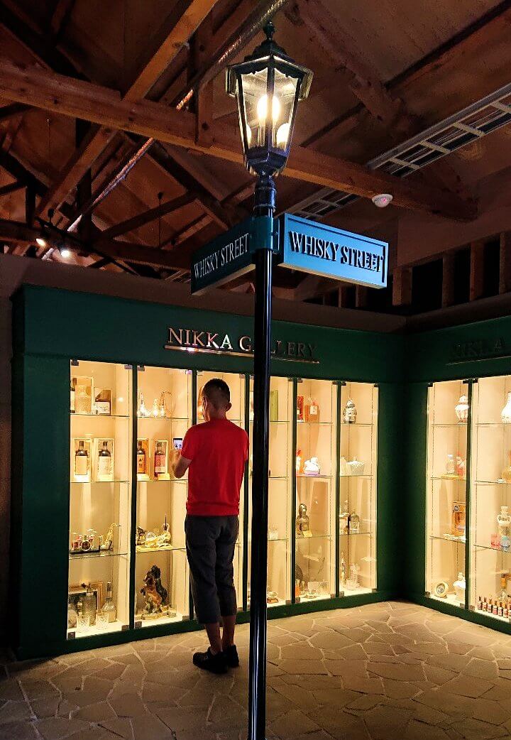 余市町のウイスキー博物館内に展示されているお酒を眺める男