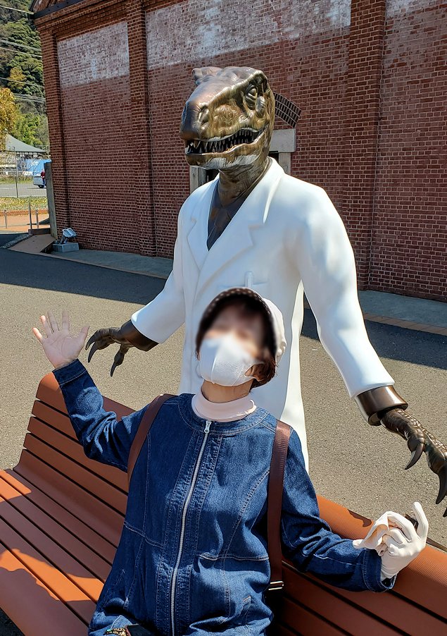 敦賀市　敦賀赤レンガ倉庫の前に立つ、フクイラプトル博士像と記念撮影